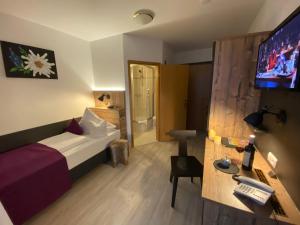 ein Hotelzimmer mit einem Bett, einem Schreibtisch und einem TV in der Unterkunft Sascha's Kachelofen in Oberstdorf
