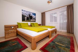 a bedroom with two beds with yellow and green pillows at Apartment Aura in Zermatt