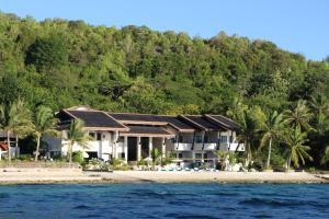 uma casa numa praia com palmeiras e água em Emoha Dive Resort em Oslob