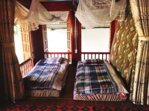 two beds in a room with two windows at Shan Tea Homestay in Ha Giang