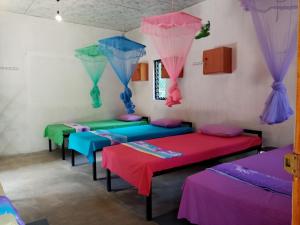 a room with four beds with umbrellas at Helena Hostel in Dickwella