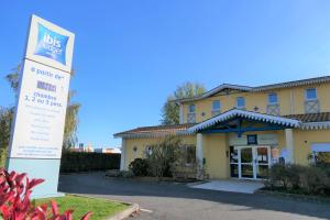 un bâtiment avec un panneau devant lui dans l'établissement Ibis Budget Perigueux Boulazac, à Boulazac