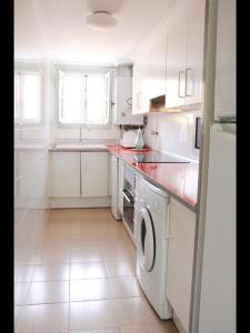 ポルト・サプラヤにあるCozy apartment on the seaのキッチン(白いキャビネット、洗濯機、乾燥機付)