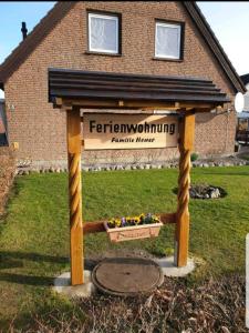 ein Holzschild für einen Garten vor einem Haus in der Unterkunft Ferienwohnung Heuer in Fehmarn