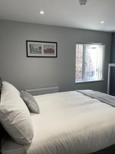 a bedroom with a bed with white sheets and a window at Brownlows Inn Rooms formerly Riley's Rooms in Liverpool