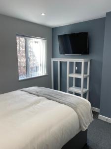 a bedroom with a bed and a flat screen tv at Brownlows Inn Rooms formerly Riley's Rooms in Liverpool