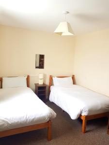 two beds in a room with white sheets at Ingoldale House in Ingoldmells
