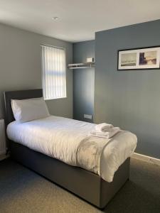 a bed in a bedroom with a blue wall at Brownlows Inn Rooms formerly Riley's Rooms in Liverpool