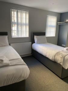 a bedroom with two beds and two windows at Brownlows Inn Rooms formerly Riley's Rooms in Liverpool