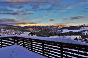 Un balcón cubierto de nieve con vistas a las montañas. en Apartmány Hutisko 769, en Hutisko