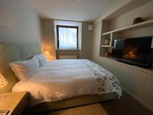 a bedroom with a white bed and a television at Maison Vittorio in Cogne