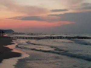 a person walking on a beach with a pier at Kleiner Bungalow - Zum Strand 50m in Ueckeritz