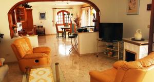 sala de estar con sillas de color naranja y TV en Sunny house with private pool and sea view, en Adeje