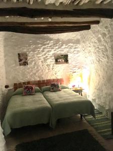 a bedroom with a bed in a stone wall at Apartamento El Refugio de Mecina in Mecina Fondales