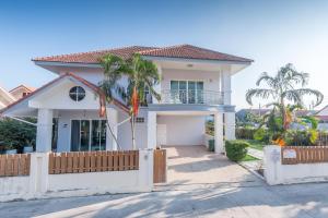 una casa bianca con una recinzione e palme di Baan Kiang Lay Phu View Hua Hin Private Pool Villa บ้านเคียงเลภูวิว ไพร์เวท พูลวิลล่า กลางเมือง ใกล้หาดหัวหิน a Hua Hin