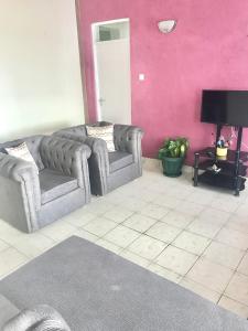 ein Wohnzimmer mit 2 Sofas und einer rosa Wand in der Unterkunft Bandari apartment in Mombasa