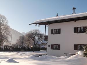 ein weißes Gebäude mit Schnee auf dem Boden in der Unterkunft Landhaus Pichler in Ruhpolding
