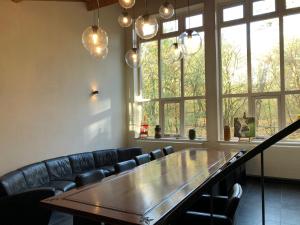 a table and chairs in a room with windows at Het Atelier, ruime vrijstaande vakantiewoning 200m2 voor maximaal 8 personen in Leende