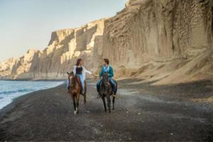 zwei Menschen reiten auf einem felsigen Strand in der Unterkunft 360 Blue in Fira