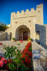 a stone building with red flowers in front of it at Cassiopeia's Castle in Gythio