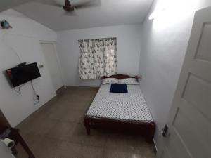 a small bedroom with a bed and a television at Beachway Inn in Alleppey