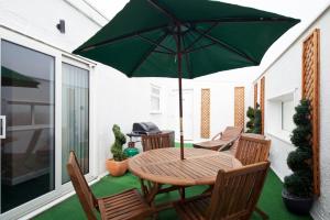 a wooden table and chairs with an umbrella on a patio at Queens Mansions: Queens Suite in Blackpool