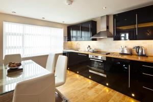 a kitchen with black cabinets and a table with white chairs at Queens Mansions: Queens Suite in Blackpool