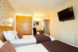 a hotel room with two beds and a flat screen tv at Queens Mansions: Princess Suite in Blackpool