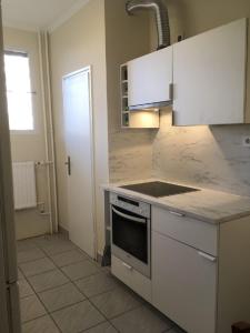 a kitchen with white cabinets and a stove top oven at Harangláb Apartman Tata in Tata +8 photos