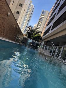 a swimming pool in front of some tall buildings at Apart Estanconfor Santos in Santos