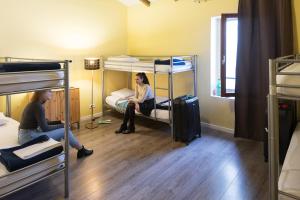 Dos mujeres sentadas en una habitación con literas en Hostel Vertigo Vieux-Port en Marsella