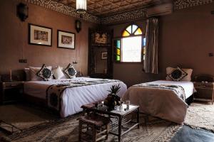 1 dormitorio con 2 camas, mesa y ventana en Riad Ouarzazate, en Ouarzazate