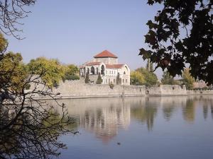 a large building sitting on the side of a lake at Harangláb Apartman Tata in Tata