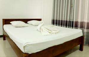 a bed with white sheets and pillows in a room at Kanora lake resort in Maharagama