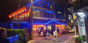 a group of people standing outside of a building with blue lights at Jiufen Let's go Bed and Breakfast in Jiufen