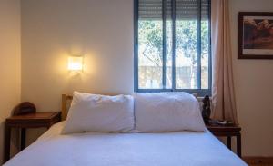 Schlafzimmer mit einem Bett mit weißer Bettwäsche und einem Fenster in der Unterkunft Netta's Place in Mitzpe Hila