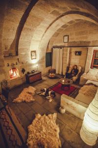 a man and two dogs sitting in a room with a fireplace at Asmalı Cave House in Uchisar