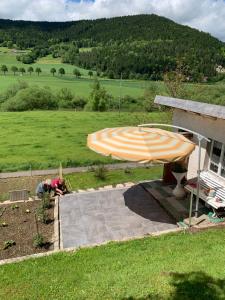 Eine Frau, die in einem Garten unter einem Schirm arbeitet. in der Unterkunft La Maisonnette in Travers