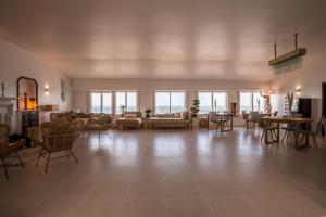 a large living room with chairs and tables and windows at Sandhi House - Yoga & Wellness in Ericeira