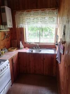uma cozinha com um lavatório e uma janela em Cabaña San Vicente em llifen