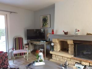 uma sala de estar com lareira e televisão em Ma demeure em Le Gué-de-Longroi