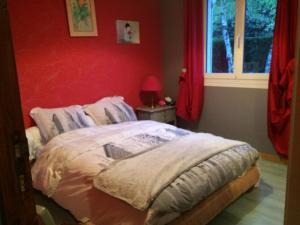 a bedroom with a bed with a red wall at Ma demeure in Le Gué-de-Longroi