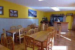 a restaurant with wooden tables and chairs and a counter at Albergue La Vargona in Camaleño