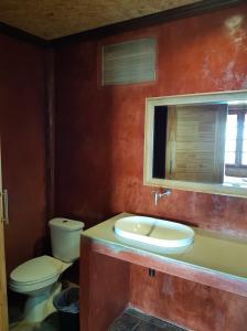 a bathroom with a toilet and a sink and a mirror at Bottle Beach 2 Bungalows in Bottle Beach
