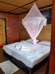 a bed with a mosquito net on top of it at Bottle Beach 2 Bungalows in Bottle Beach