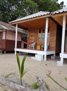 a small house with a hammock in front of it at Bottle Beach 2 Bungalows in Bottle Beach