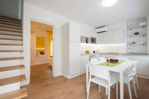 una cucina e una sala da pranzo con tavolo e sedie bianchi di ZONA 30 Bike Guesthouse a Palmanova
