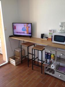 einen Schreibtisch mit einem TV und Hockern in einem Zimmer in der Unterkunft Au calme dans hameau fleuri joli Studio 3 pers piscine parking wi-fi in Vence