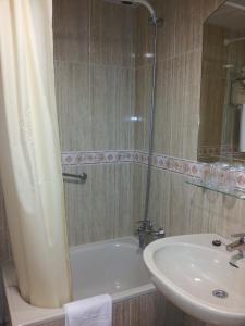 een badkamer met een douche, een wastafel en een bad bij Begoña Playa in Gijón
