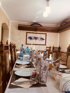 Leaganul Bucovinei Guest House في سوسيفا: غرفة طعام مع طاولة طويلة مع الأطباق والفضيات